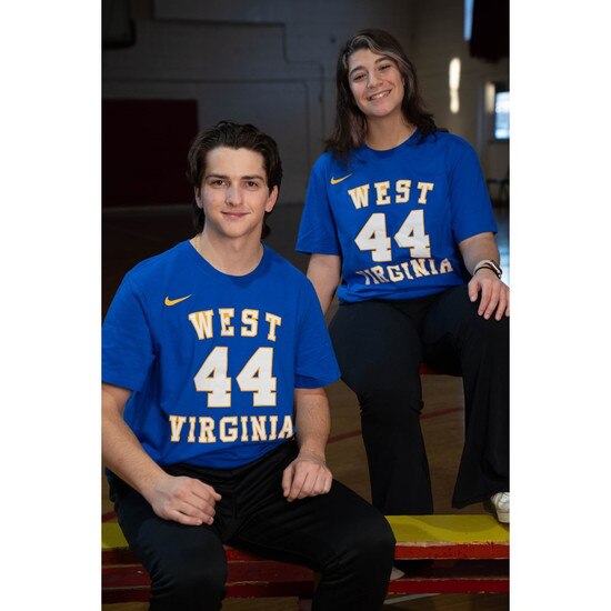 Two models both wearing the royal blue Nike WVU Jerry West tee with West over #44 over Virginia on the front