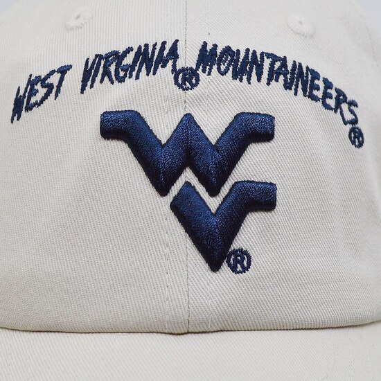 Close up of the West Virginia Mountaineers arched over the a Flying WV embroidered in navy on the front panel of the grey youth WVU cap
