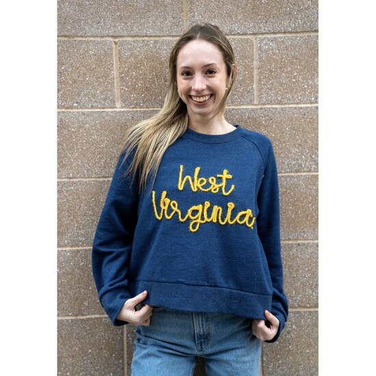 Model wearing the navy women's pullover crew with West Virginia in metallic gold rope yarn embroidery